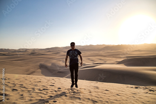 young man on sand in a desert near Huacachina  Ica region  Peru. The sunset desert view