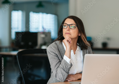 Businesswoman thinking about work while sitting at her office desk photo