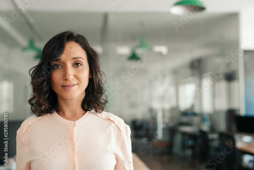Smiling young businesswoman standing alone in a large office