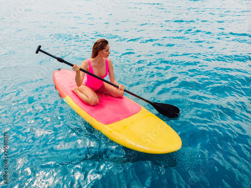 Photography Attractive woman on stand up paddle board on a quiet blue ocean