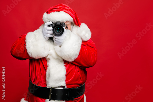 Portrait of focused elderly santa claus hipster take photo of his christmas time voyage abroad wear stylish costume belt gloves isolated over red background