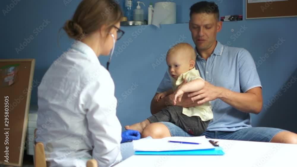 Young man brought his one and a half year old son to a doctor for examination by a pediatrician. Workplace pediatrician Young man brought his one and a half year old son to a doctor for examination by a pediatrician. Workplace pediatrician