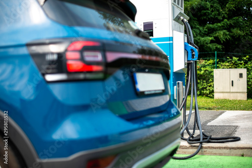 Electric car on gas station. Blue car and electric plug for charging. photo