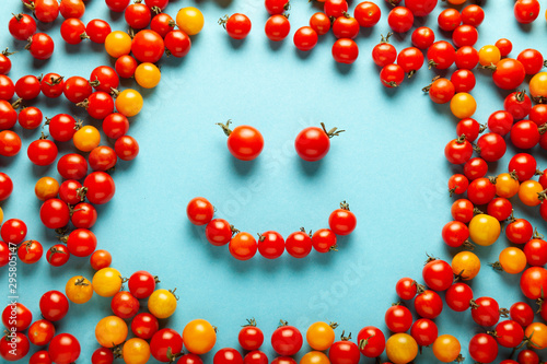 Red and yellow cherry tomatoes, fresh bright organic vegetables. Smiling face.