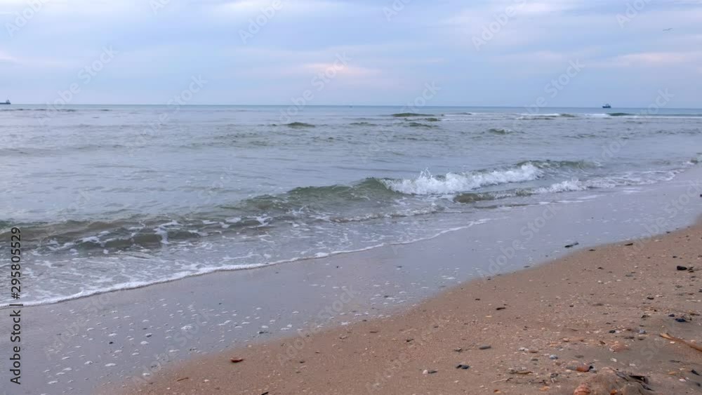 Sandy sea beach with small waves and ships on distance in evening. Beautiful nature seascape with stormy winter sea and cloudy sky in twilight. Sandy sea beach with small waves and ships on distance in evening. Beautiful nature seascape with stormy winter sea and cloudy sky in twilight.