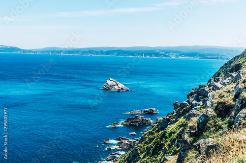rock cliff in the ocean with blue water and sunny sky