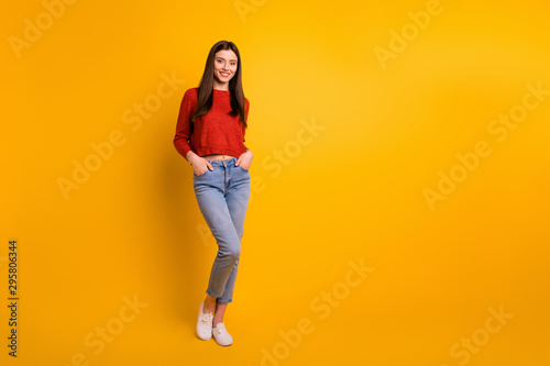 Full length body size photo of cute nice attractive millennial youngster with hands in pockets standing near empty space smiling toothily isolated over vivid color background