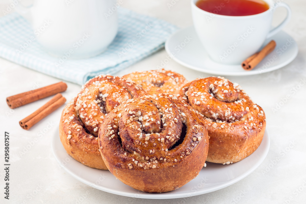 Cinnamon buns on a white plate, served with cup of red tea, horizontal Cinnamon buns on a white plate, served with cup of red tea, horizontal