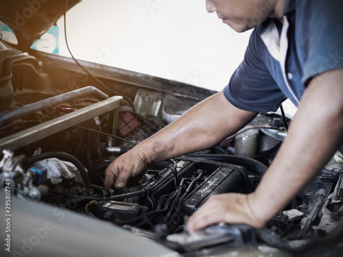 Car mechanic is holding a screwdriver on the engine of a motor car during a service. Repair in an automotive workshop.