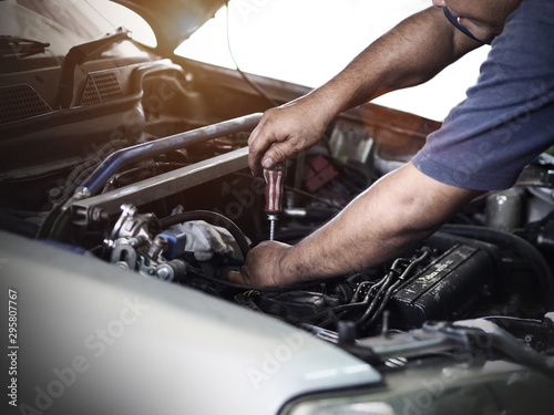 Car mechanic is holding a screwdriver on the engine of a motor car during a service. Repair in an automotive workshop.