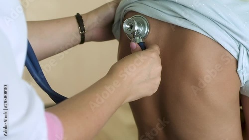 pediatrician examines back of teenage girl. woman doctor listens to  baby's breathing and heartbeat with a stethoscope. Cold and prescribed treatment. Medical examination of the patient in the office.
