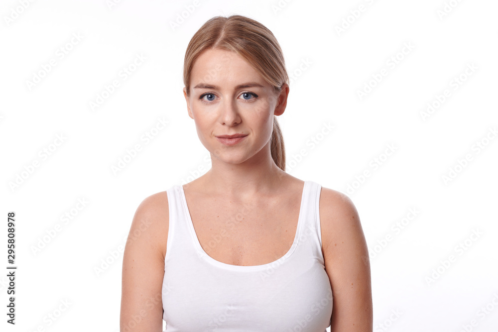 Attractive slender young woman in jeans and a white summer top standing looking intently at the camera with a quiet smile isolated on white Attractive slender young woman in jeans and a white summer top standing looking intently at the camera with a quiet smile isolated on white