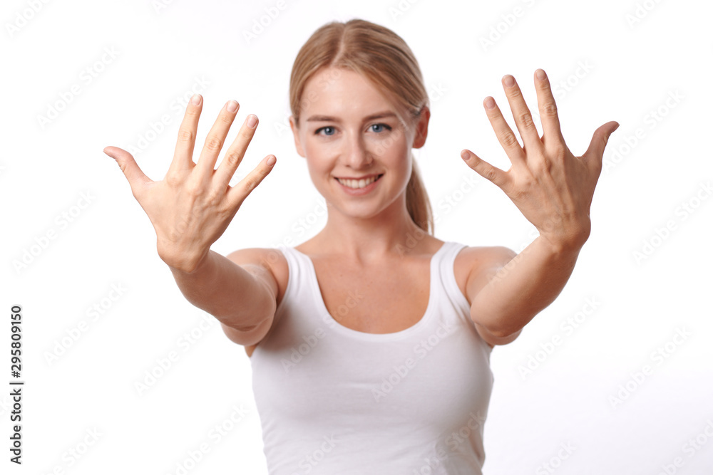 Smiling friendly young woman showing her hands with her fingers splayed towards the camera isolated on white Smiling friendly young woman showing her hands with her fingers splayed towards the camera isolated on white