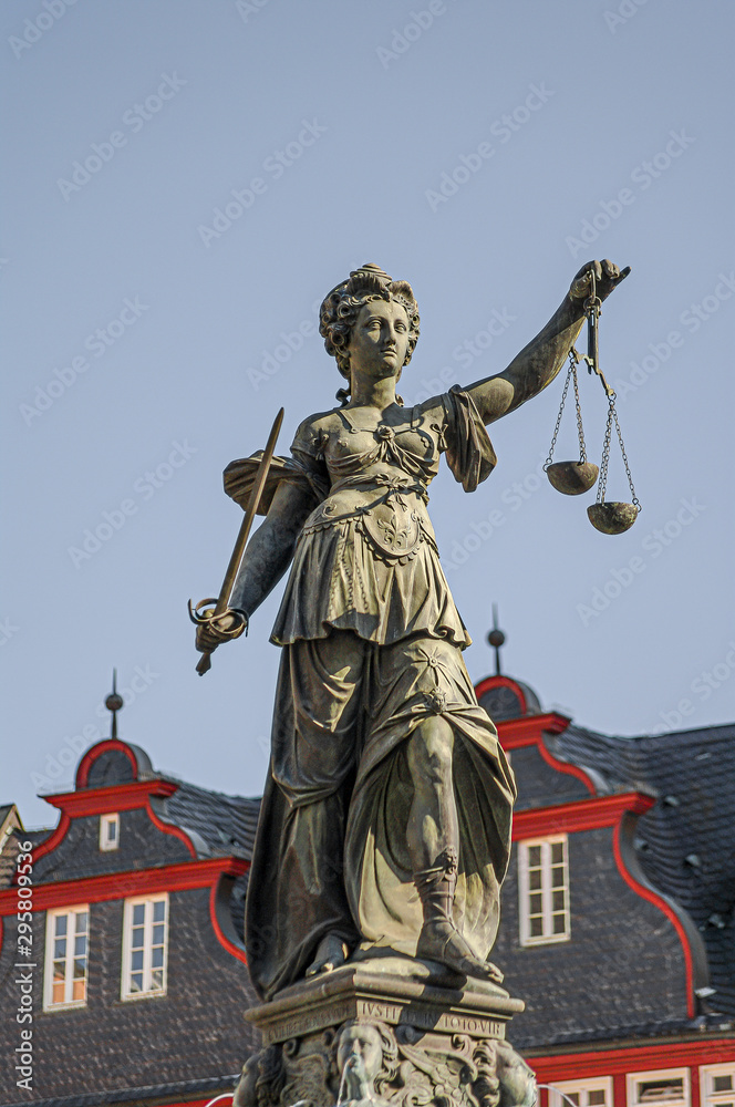 Statue a judge woman with scales and sword with old traditional wooden made houses in downtown of Frankfurt, Germany, details, closeup