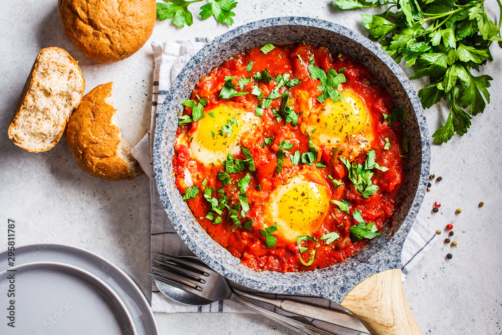 Traditional shakshuka in  pan. Fried eggs in tomato sauce with herbs, top view.
