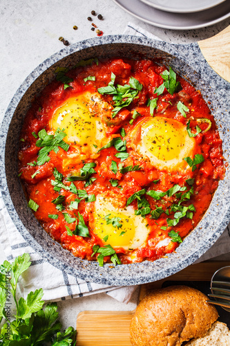 Traditional shakshuka in  pan. Fried eggs in tomato sauce with herbs, top view.