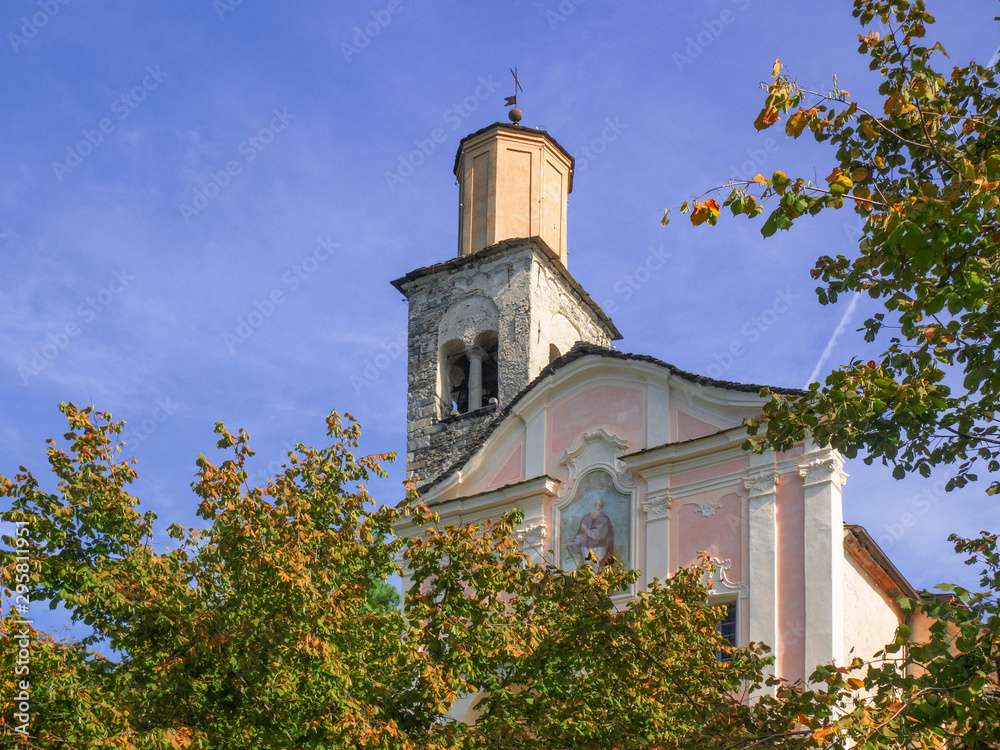 a country church on a sunny day, peeking through the trees of a forest in the colors of autumn