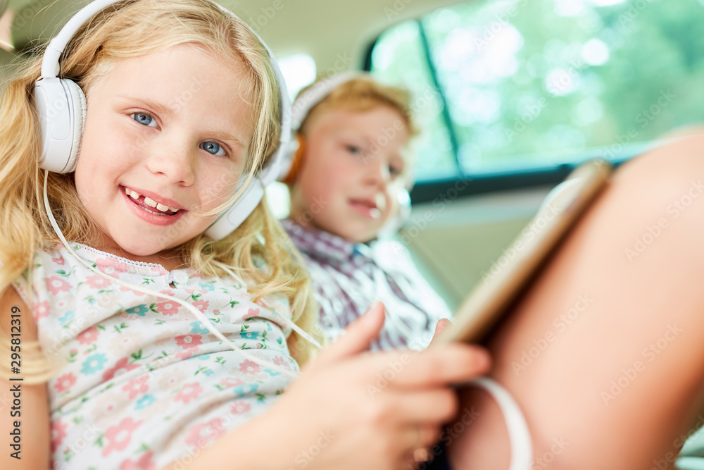 Fototapeta premium Children in the car listen to music with headphones