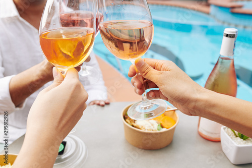 Close-up image of peope drinking rose wine when having fun at outdoor pool party photo