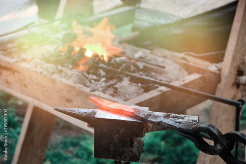 Hot knife blade on the anvil. Workpiece in the forge on the background of the fire. The heat from the stove and the blade of the forged sword. photo