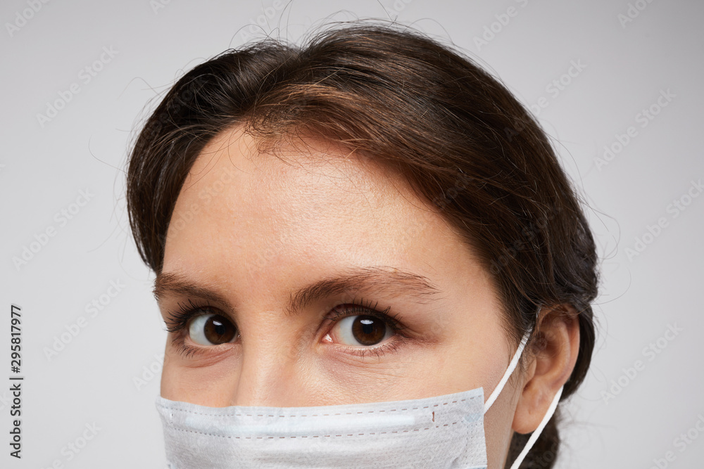 Close up portrait of female doctor wearing protective mask and looking at camera posing against white background Close up portrait of female doctor wearing protective mask and looking at camera posing against white background