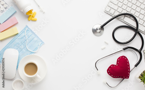 Medical instruments with pills near cloth heart and wireless equipment over white surface