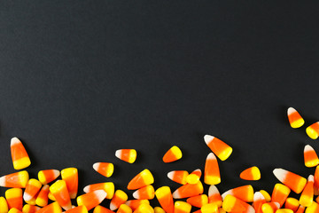 Bunch of candy corn sweets as sybol of Halloween hoiday on textured background with a lot of copy space for text. Flat lay composition for all hallows eve. Top view shot.