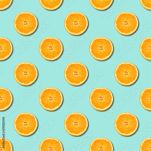 Seamless pattern of orange sliced on neo mint green color background. Minimal, flat lay, food texture.