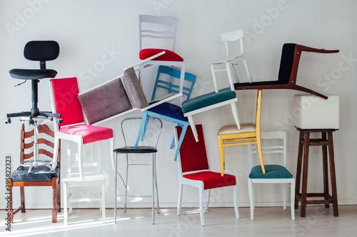 many different chairs stand in the white room