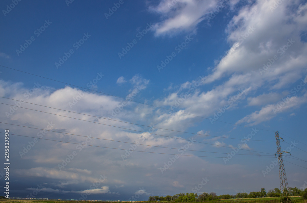 Blue sky with cirrus clouds and power lines in the far.