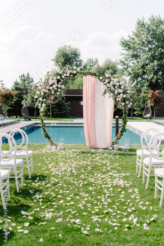 Wedding decor for garden wedding in summer. Round arch decorated with greens and pink cloth