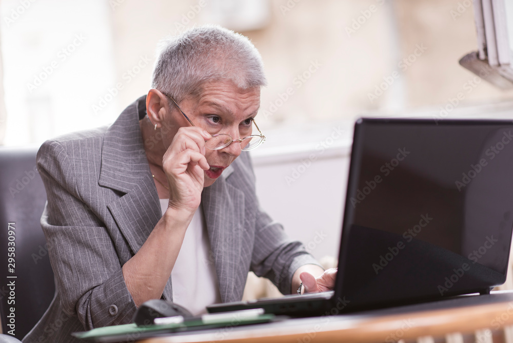 Senior old business lady in disbelief by an email on her laptop