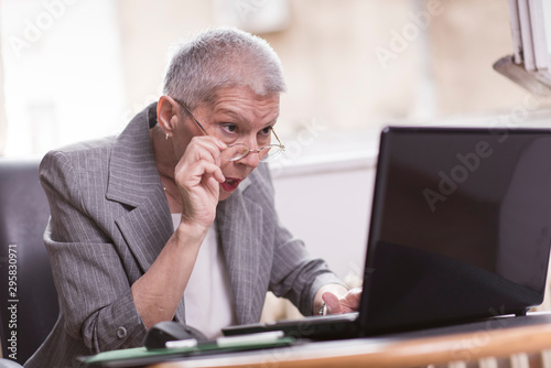 Senior old business lady in disbelief by an email on her laptop