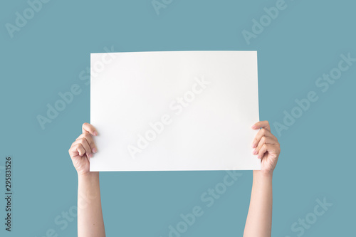 hand holding white blank paper isolated on blue background with clipping path