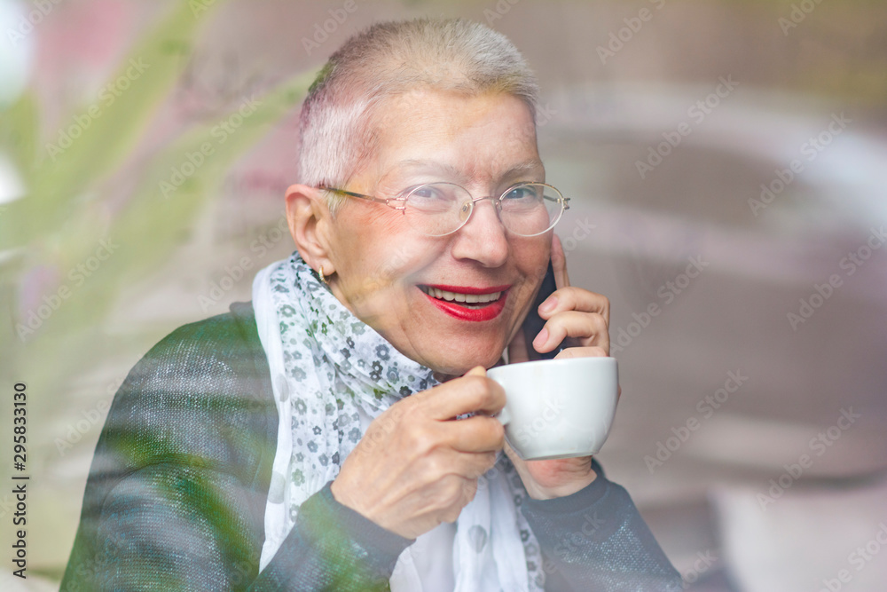 Cheerful old lady talking on her telephone at a coffee shop, looking joyous Cheerful old lady talking on her telephone at a coffee shop, looking joyous