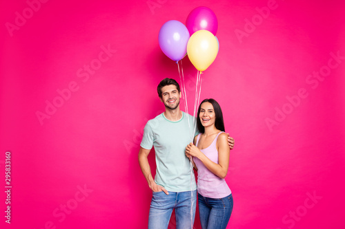Photo of funny guy and lady couple holding air balloons in hands came to parents birthday party wear casual outfit isolated pink color background