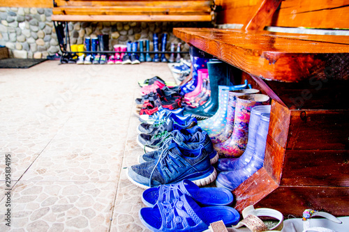 neat row of children's shoes for off-season weather under the bench - sandals, sandals, sneakers and rubber boots © Kira