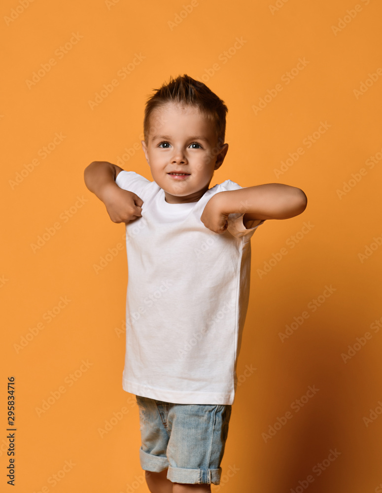 Kid boy is posing with his hands at in his shoulders like he held a banner to his chest showing us the writing on it Kid boy is posing with his hands at in his shoulders like he held a banner to his chest showing us the writing on it