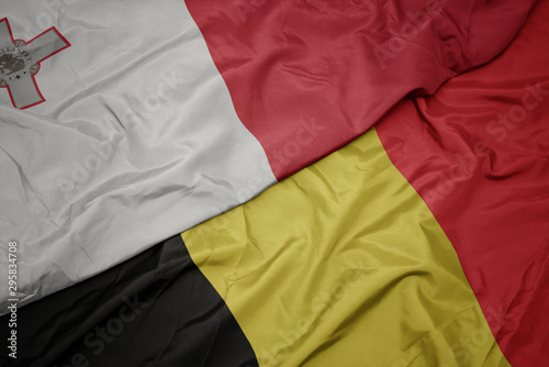 waving colorful flag of belgium and national flag of malta.