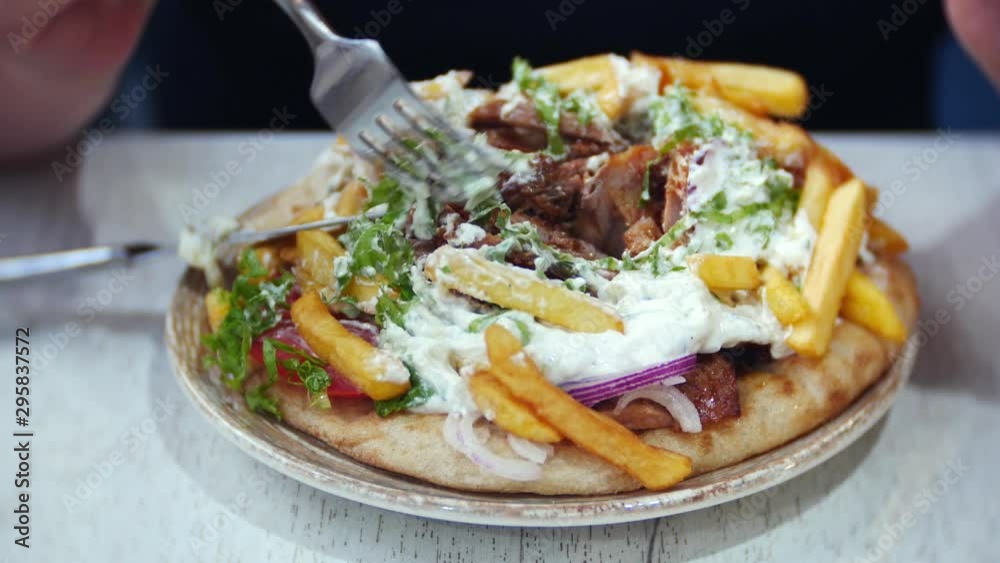 Souvlaki and gyro, a traditional Greek dish. Female hands holding a fork close-up. Souvlaki and gyro, a traditional Greek dish. Female hands holding a fork close-up.