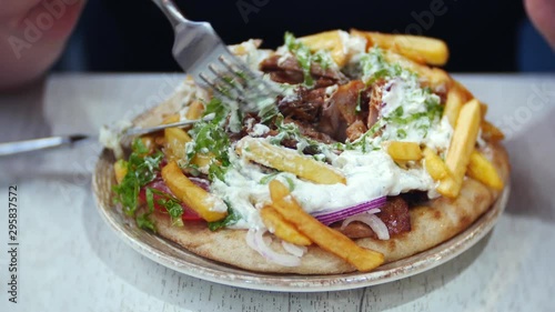Souvlaki and gyro, a traditional Greek dish. Female hands holding a fork close-up.