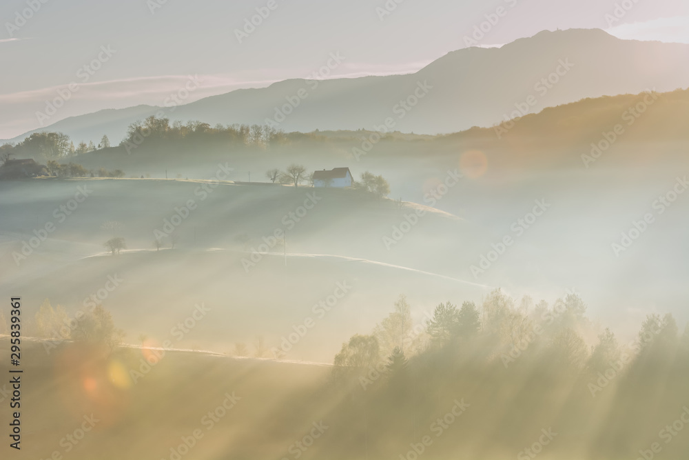 Beautiful scenery landscape Romania village mountains hills fields foggy morning first ray splitting light