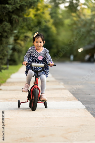 Cute little Asian girl learning ride a bicycle without wearing a helmet © Kenishirotie