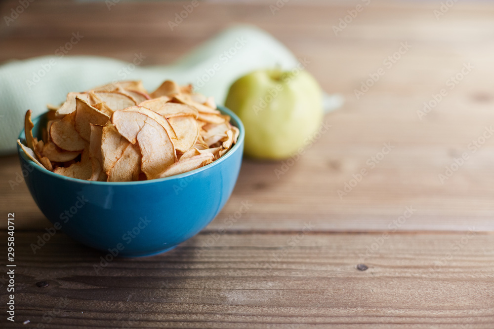 The concept of useful raw food diet. Apple chips and apple on a wooden background The concept of useful raw food diet. Apple chips and apple on a wooden background