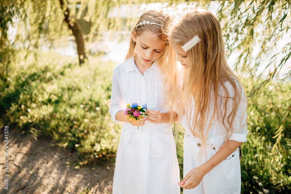 little children play in the park, two girls with long hair have rest outdoors little children play in the park, two girls with long hair have rest outdoors