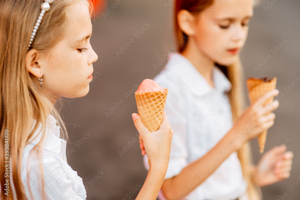 Little beautiful girls eat ice cream outdoors