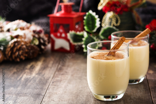 Homemade eggnog with cinnamon in glass on wooden table. Typical Christmas dessert. photo