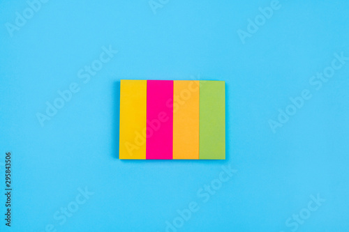 Sets of bright colored stickers in the form of stripes of yellow, pink, orange, green color transparent tablets located in the center on a blue background. A place for advertising and recordings.