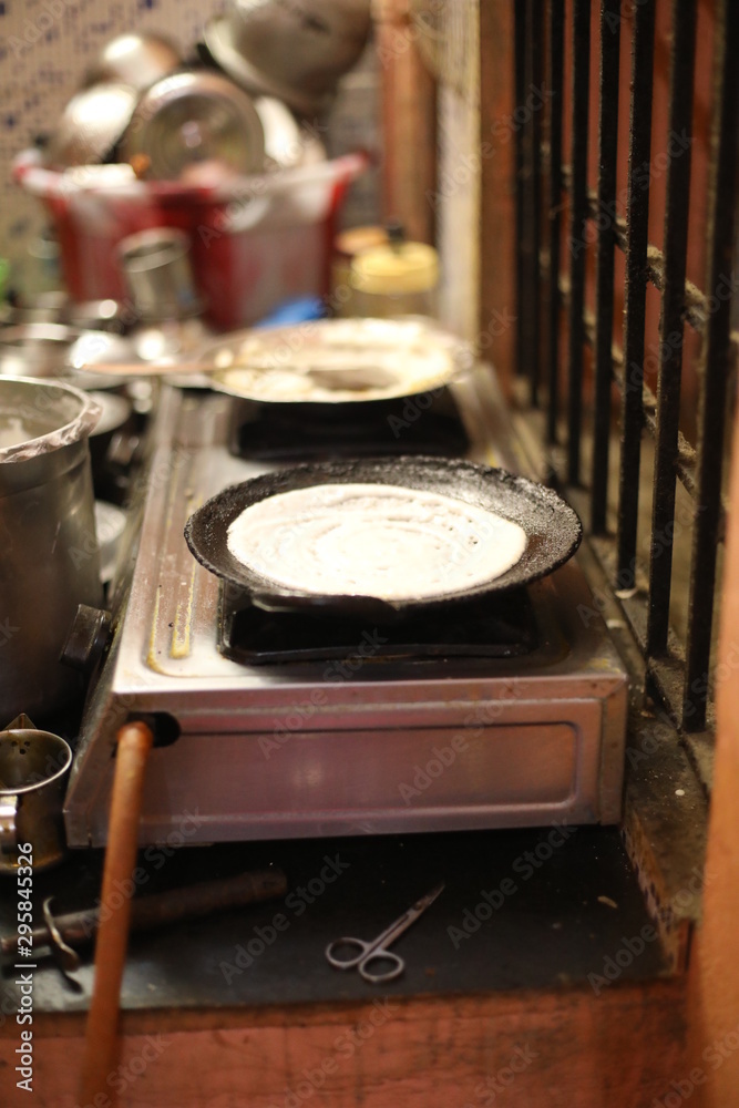 cooking dosa in kitchen, India. South Indian vegetarian, traditional and popular breakfast.