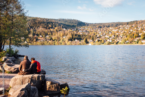 un couple d'amoureux devant le lac de Gérardmer. Des gens assis devant un lac. Des amoureux regardant un lac. Le lac de Gérardmer dans les Vosges. L'automne dans les Vosges.